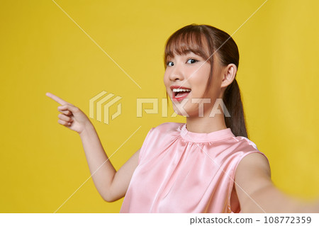 Young woman make selfie very happy pointing with hand and finger to the side Young woman make selfie very happy pointing with hand and finger to the side 108772359