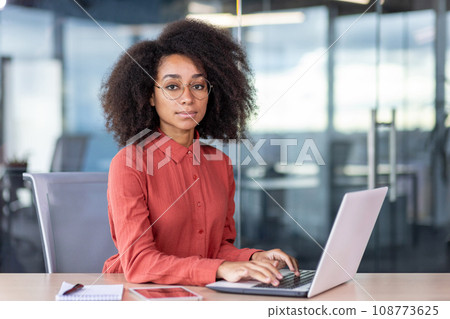 Serious focused woman working inside office with laptop, business woman looking thinking at camera, thoughtful and successful worker. 108773625