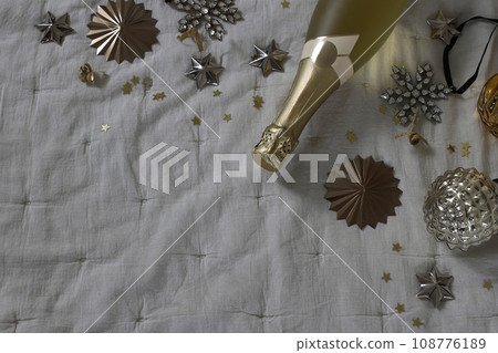 Moody new year party, celebration banner. Bottle of champagne wine, vintage Christmas balls, baubles and golden star confetti decor. Muslin tablecloth. Birthday, anniversary concept. Flat lay, top Moody new year party, celebration banner. Bottle of champagne wine, vintage Christmas balls, baubles and golden star confetti decor. Muslin tablecloth. Birthday, anniversary concept. Flat lay, top 108776189