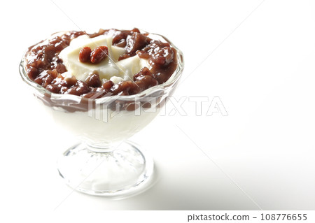 A photo of plenty of red bean paste and almond tofu served in a dessert cup against a white background 108776655