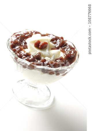 A photo of plenty of red bean paste and almond tofu served in a dessert cup against a white background 108776668
