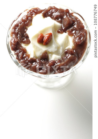 An overhead shot of plenty of red bean paste and almond tofu served in a dessert cup against a white background 108776749