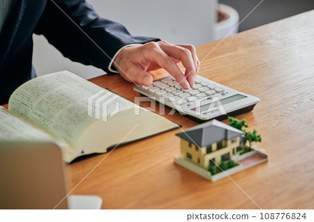 一位男律師一邊看《六法全書》一邊用計算機計算 一位男律師一邊看《六法全書》一邊用計算機計算 108776824