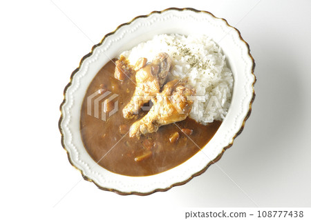 An overhead shot of hot curry rice with bone-in chicken on a white background 108777438