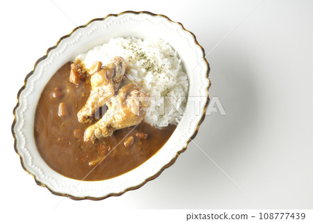An overhead shot of hot curry rice with bone-in chicken on a white background 108777439