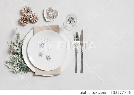 Festive table setting with Christmas silver decorations on white background. New Year serving with a copy space. Copy space, top view, flat lay. Festive table setting with Christmas silver decorations on white background. New Year serving with a copy space. Copy space, top view, flat lay. 108777706