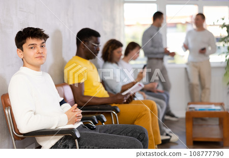 Young male visitor sitting on the bench in waiting room of clinic Young male visitor sitting on the bench in waiting room of clinic 108777790