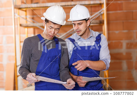 Workers holding papers with blueprints 108777802