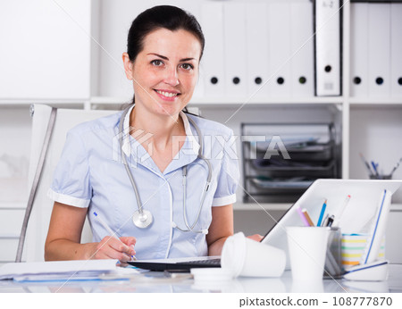 Medical worker with stethoscope writing recipe 108777870