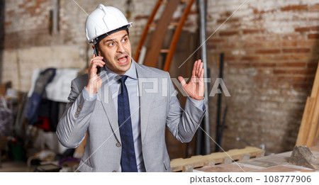 Unhappy male architect talking on phone 108777906