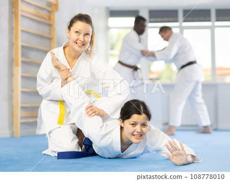 Middle-aged woman twisting her opponent's arm on the floor Middle-aged woman twisting her opponent's arm on the floor 108778010
