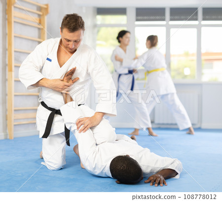 Middle-aged man twisting his opponent's arm on the floor Middle-aged man twisting his opponent's arm on the floor 108778012