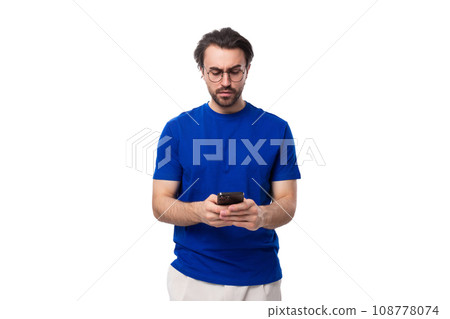 young handsome caucasian man with dark well-groomed hair and beard uses a mobile phone young handsome caucasian man with dark well-groomed hair and beard uses a mobile phone 108778074