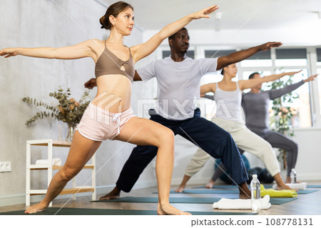 Young woman with multinational group of sporty adult people training stretching workout in yoga studio 108778131