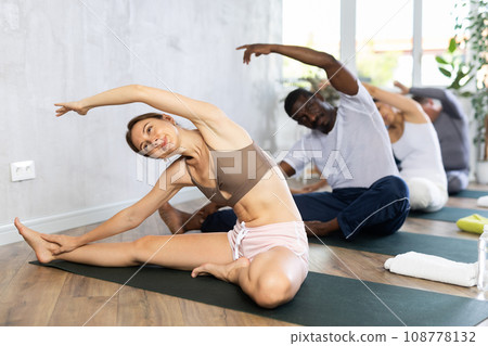 Young woman doing Parivrtta Janu Sirsasana during group yoga training 108778132