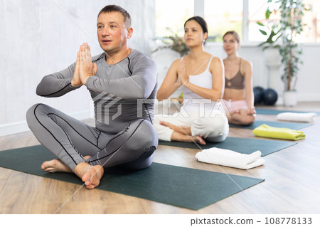 Group different nationality people practise yoga, meditation in lotus position in fitness center 108778133