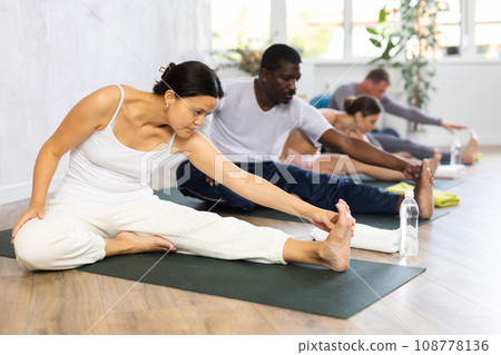 Young woman practicing yoga in group in studio 108778136