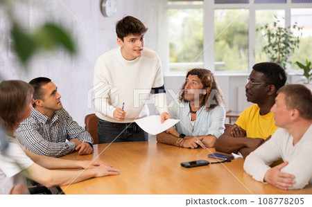 Guy discussing study topics with male coursemates at table 108778205