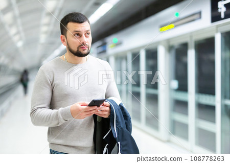 Portrait of confident man traveling on subway and using smartphone 108778263
