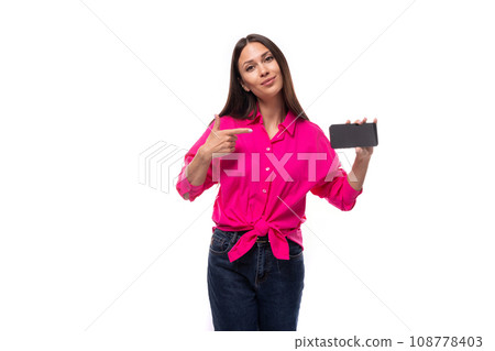 young brunette secretary woman dressed in a pink shirt shows the screen of a mobile phone with a 108778403