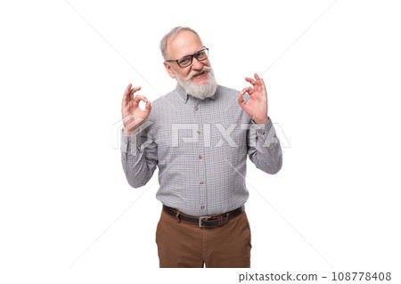 well-groomed elderly man with a gray beard and mustache in trousers and a shirt wears glasses 108778408