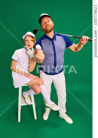Top view. Father and daughter on golf court. Dad, man and girl, teenager dressed like golf players posing on green background. 108778621