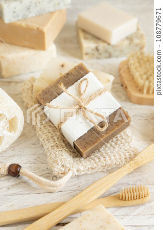 Beige handmade soap bar on soap saver bag near hygiene Items close up 108779671