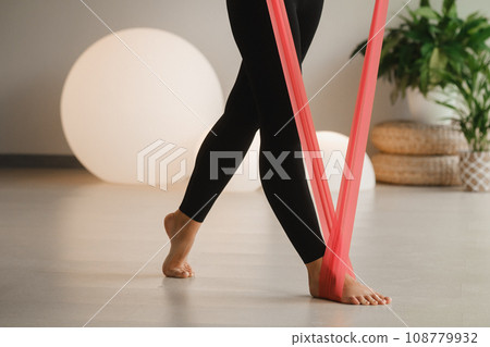 Close-up of the legs of a Girl in black doing fitness with red ribbons indoors Close-up of the legs of a Girl in black doing fitness with red ribbons indoors 108779932