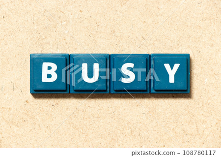 Tile alphabet letter in word busy on wood background Tile alphabet letter in word busy on wood background 108780117