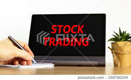 Stock trading symbol. Concept words Stock trading on beautiful black tablet. Beautiful white background. Businessman hand. Business stock trading concept. Copy space. Stock trading symbol. Concept words Stock trading on beautiful black tablet. Beautiful white background. Businessman hand. Business stock trading concept. Copy space. 108780204
