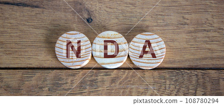 Wooden small circles with letters NDA on wood background. Concept image. 108780294
