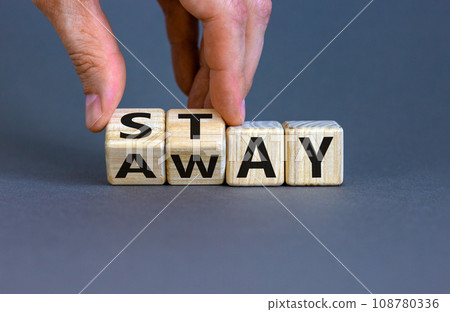 Hand turns a cube and changes the word 'away' to 'stay', or vice versa. Beautiful grey background, copy space. Business concept. 108780336
