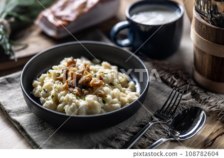 Halusky as traditional Slovak potato gnocchi with sheep cheese bryndza, fried bacon and chives 108782604