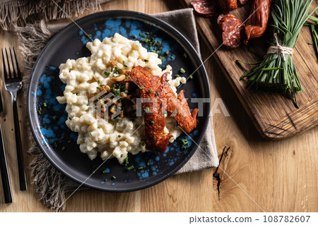 Halusky as traditional Slovak potato gnocchi with sheep cheese bryndza, fried bacon,sausage and chives Halusky as traditional Slovak potato gnocchi with sheep cheese bryndza, fried bacon,sausage and chives 108782607