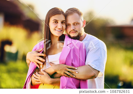 Approaching behind, husband hugs smiling wife, summer family portrait in nature. Approaching behind, husband hugs smiling wife, summer family portrait in nature. 108782631