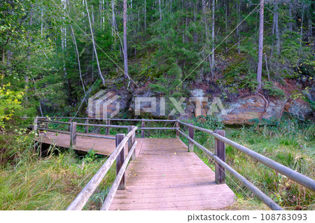 A wooden bridge, a path with a railing as a place for tourists to walk to an environmental object that is difficult to access. Red sand cliffs. Autumn in Latvia 108783093
