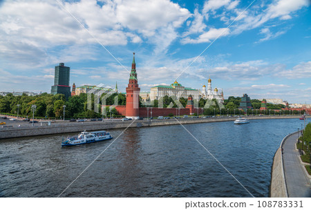 View of Kremlin with Vodovzvodnaya tower, Grand Kremlin Palace from repaired Bolshoy Kamenny Bridge in Moscow city on sunny summer day. Cruise ship sails on the Moscow river 108783331