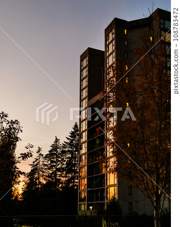 Sunset in a city. High-rise residential building on sunset sky background Sunset in a city. High-rise residential building on sunset sky background 108783472