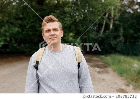 Lonely 30s man on road, concept of loneliness, depression, thoughtfulness. Male hipster Traveler with backpack. Man in active trekking clothes walking in the countryside, High quality photo 108783738