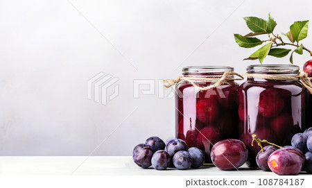 Homemade plum jam in a glass jar on a white background with space for text. 108784187