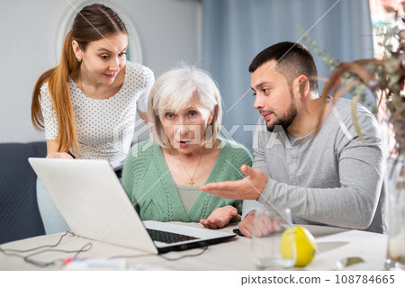 Young couple helping elderly woman use laptop Young couple helping elderly woman use laptop 108784665
