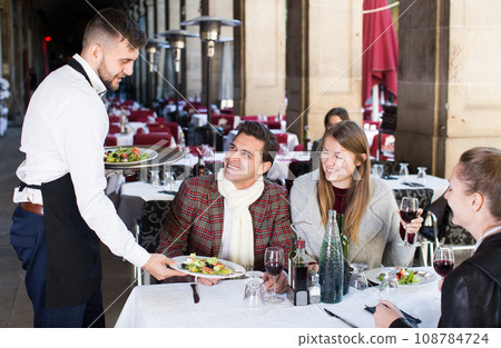 Waiter serving guests at terrace restaurant 108784724