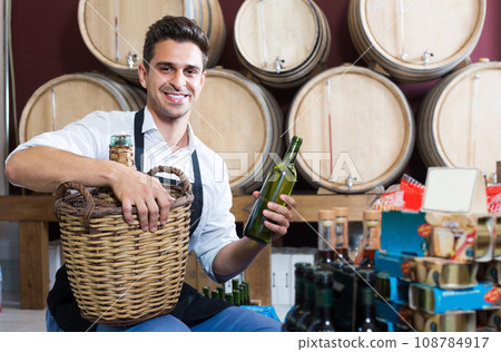 male seller with bottle in hands in cellar . 108784917