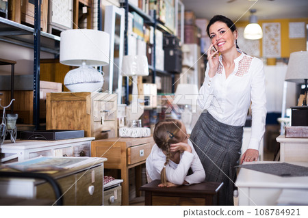 Woman with girl in furniture store Woman with girl in furniture store 108784921