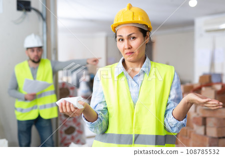 Puzzled female construction worker with displeased screaming foreman Puzzled female construction worker with displeased screaming foreman 108785532