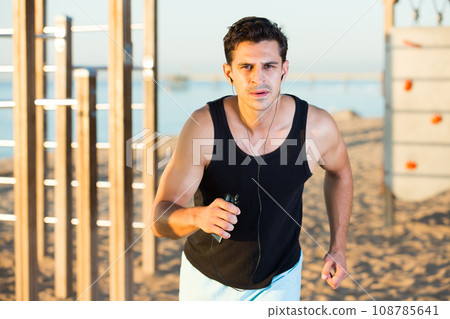 Man running on ocean beach 108785641