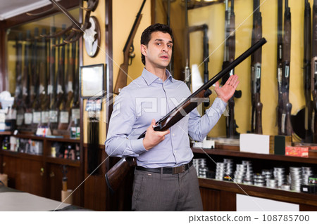 Man owner of hunting shop showing shotgun 108785700