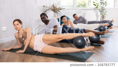 Young woman with multinational group exercising with bender balls at gym 108785777