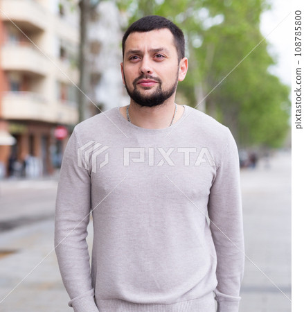 Focused bearded guy walking along city street 108785800
