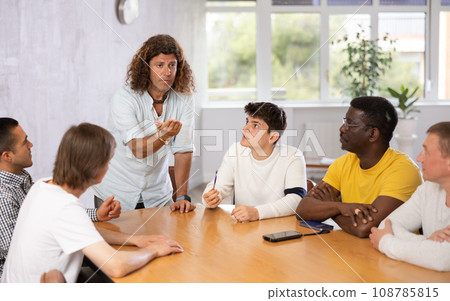 Serious team leader giving instructions to group of men Serious team leader giving instructions to group of men 108785815
